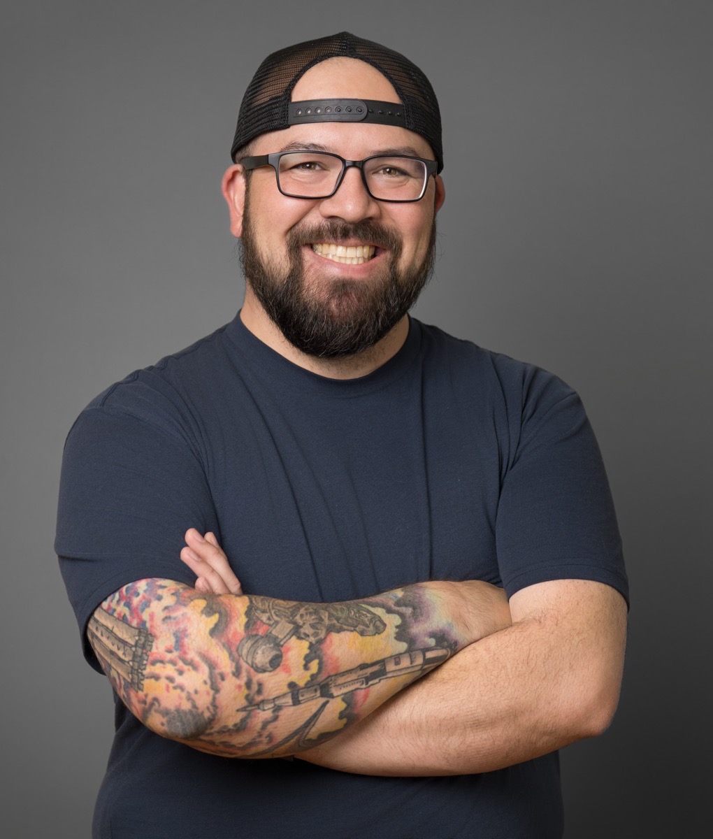 Sterling Chin smiling, wearing glasses and a backwards cap